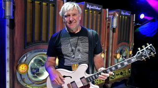 Alex Lifeson stands backstage with his white Gibson ES-355TD guitar