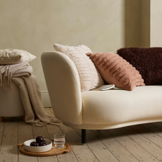 Cream sofa with fluffy neutral cushions and tray of fruit and water