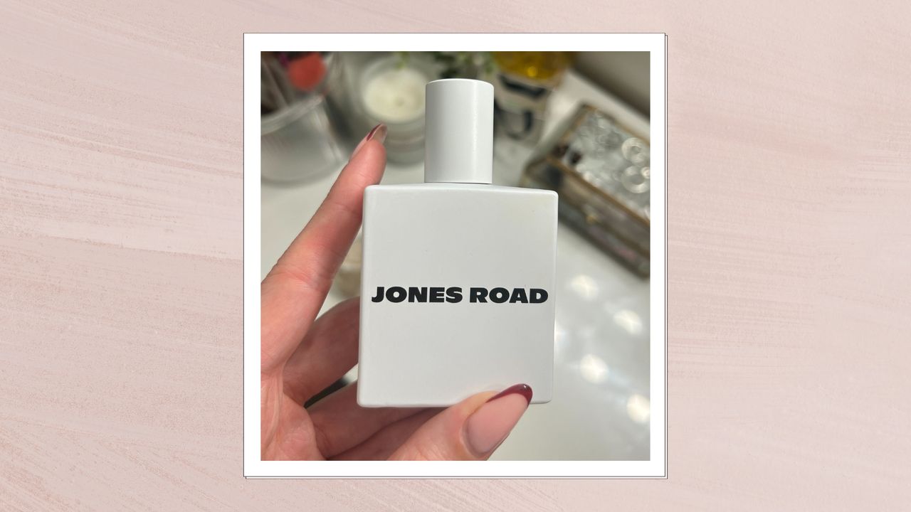 Image of hand holding Jones Road Fragrance in &#039;Shower&#039;, on a pink background