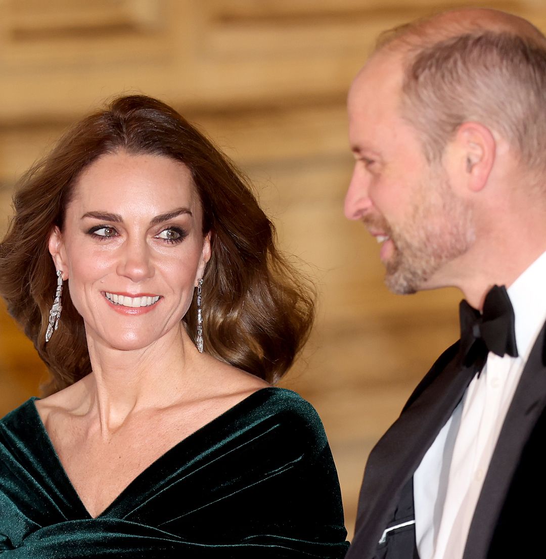 Prince William in a tux and Kate Middleton in a green gown smiling at the Royal Variety Performance