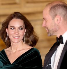 Prince William in a tux and Kate Middleton in a green gown smiling at the Royal Variety Performance