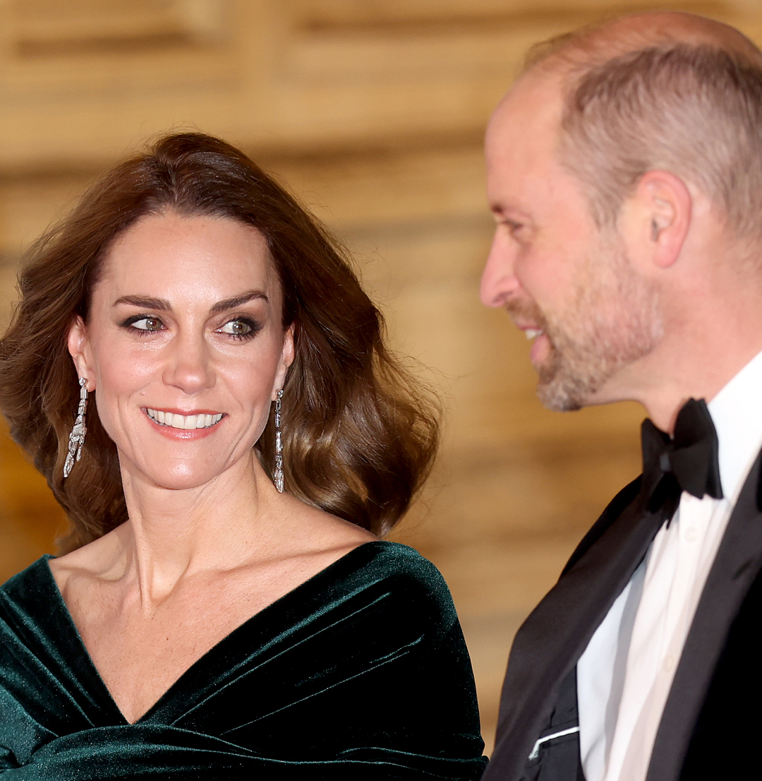Prince William in a tux and Kate Middleton in a green gown smiling at the Royal Variety Performance