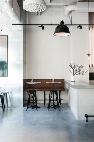 Polished concrete floor with a concrete counter and brown bench with tables and stools
