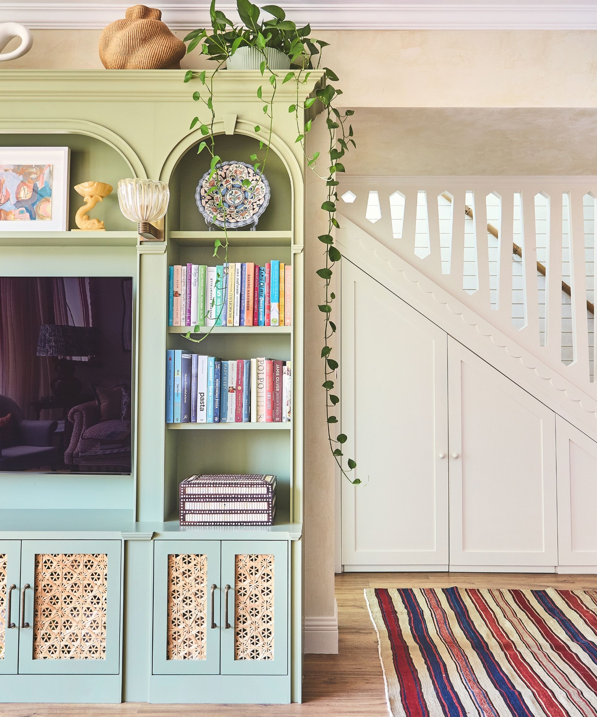 living room with patterned sofa and armchair and textured seagrass rug and colourgul painted wooden coffe table and art on walls behind with symmetrical mirrors