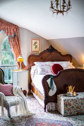 vintage style bedroom with antique bed, chintz and toile de jouy fabrics and patterned rug
