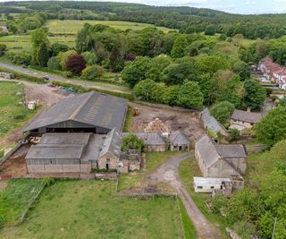 An overhead shot of a farm with a barn and acres of land and hay bales