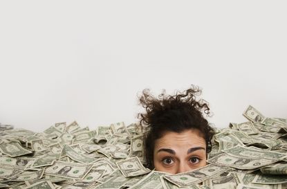 Studio shot of woman up to her eyes in money