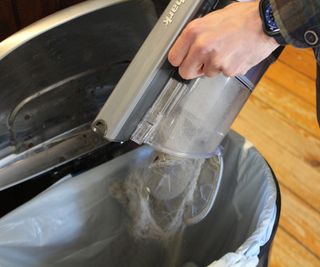 Emptying the Shark Pet Cordless Stick Vacuum in the trash