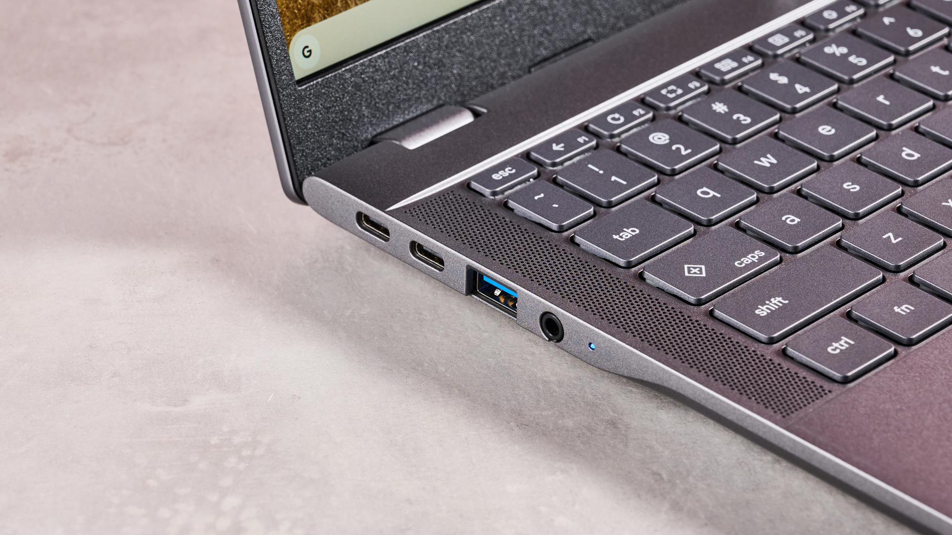 Close-up of left-side ports on Acer Chromebook Plus 516, open on desk with pink background
