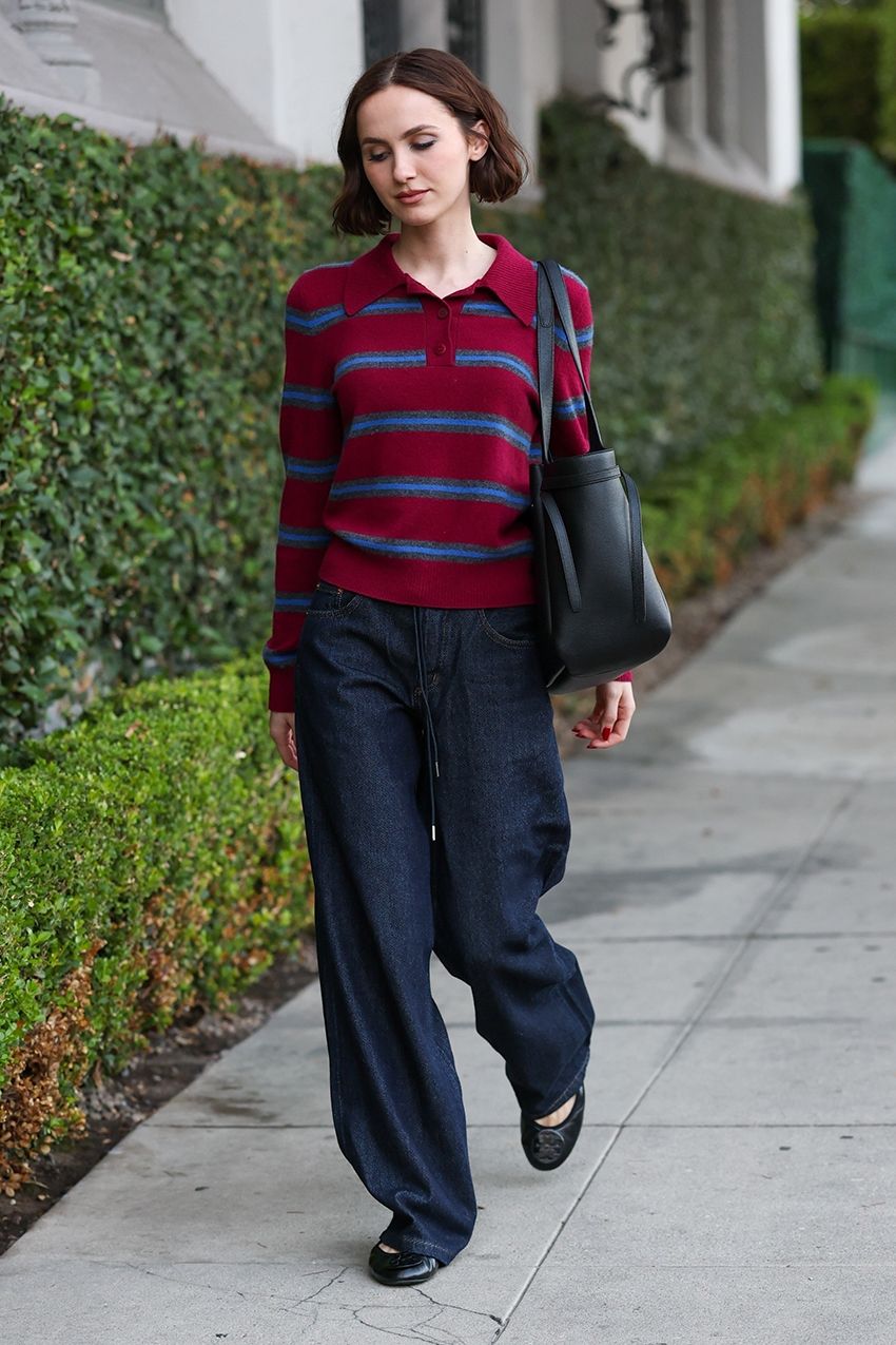 Maude Apatow wearing a burgundy striped sweater with dark denim jeans and ballet flats