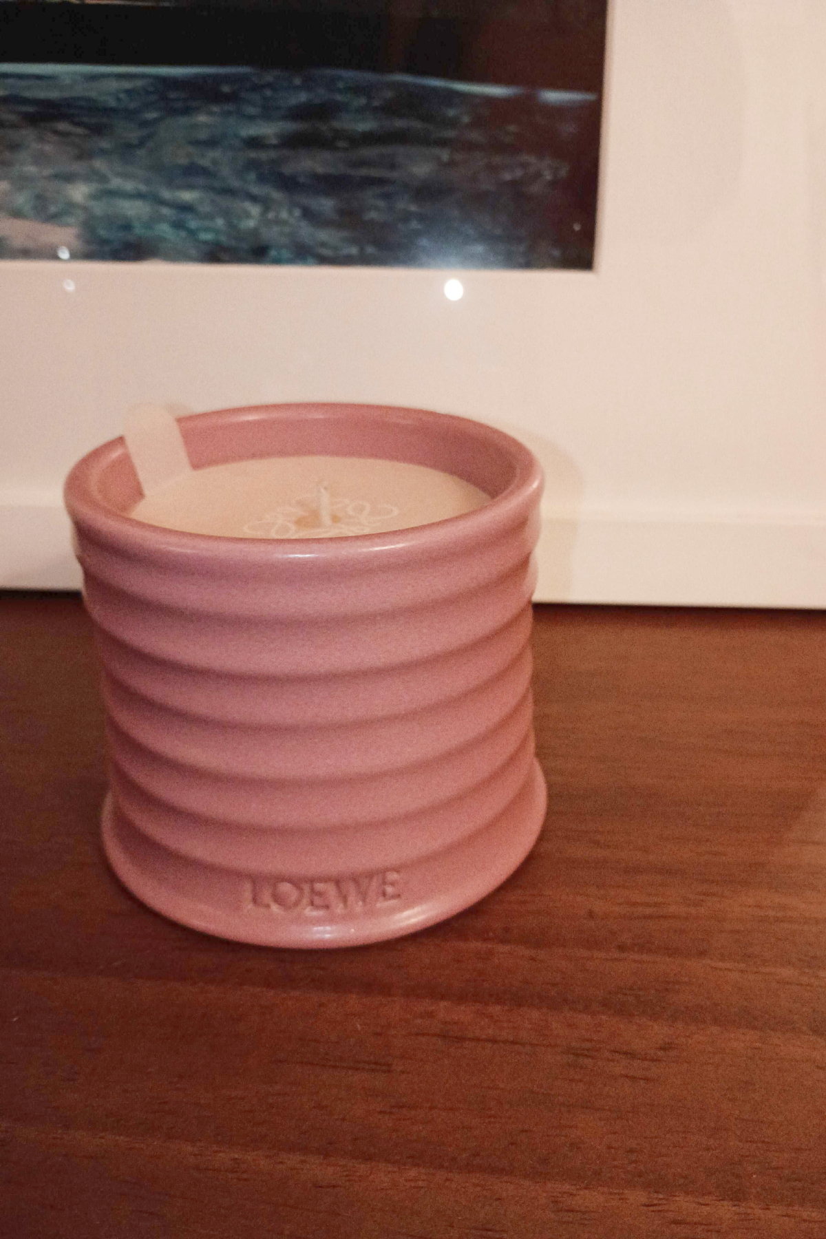 loewe ivy candle in a pink jar on a wood background