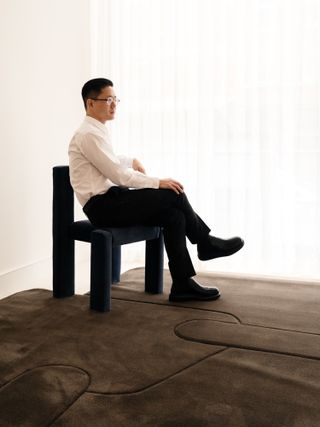 Designer Michael K Chen sitting on a chair