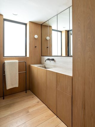 A small bathroom with wooden flooring and wooden cupboards