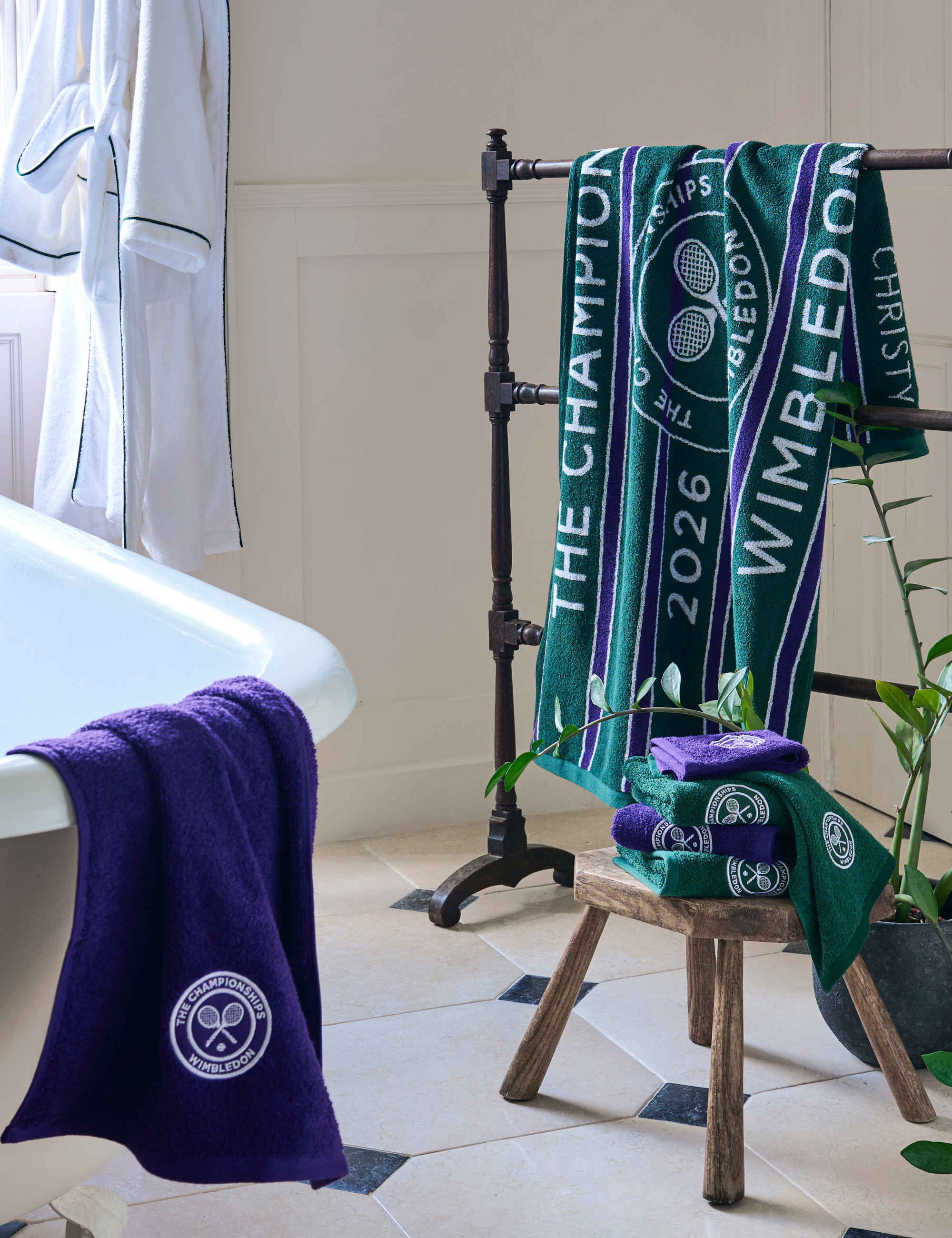 Christy x Wimbledon towels in royal purple and evergreen pictured in a charming cream-colored bathroom