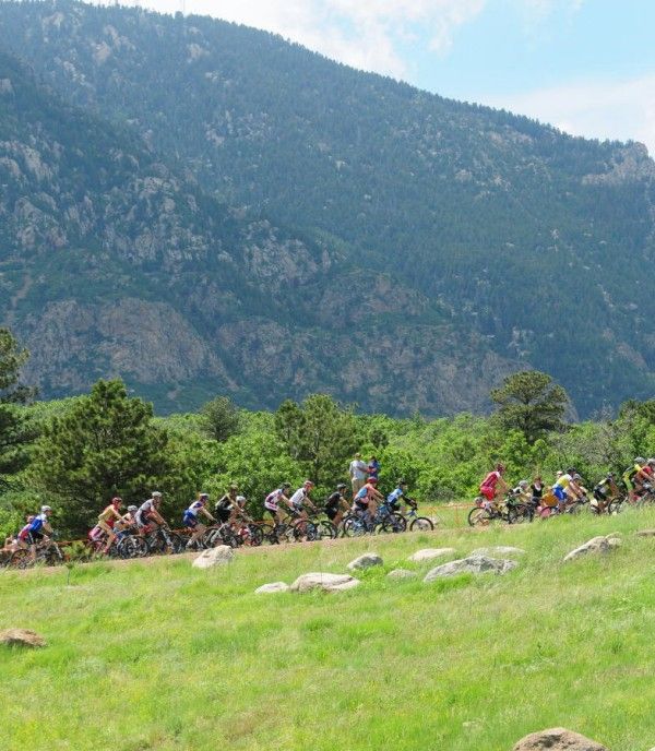 Racers ride up pavement with NORAD mountain in the background.