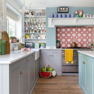 Kitchen with grey cabinets, blue island and patterned tile splashback