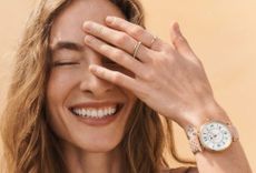 Model with her hand up to her face wearing a Fossil watch