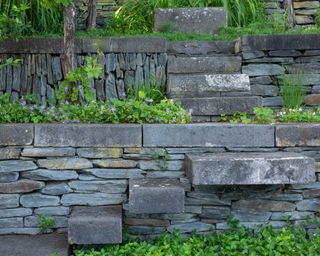 basalt rocks used as steps in dry stone wall in a sloped garden