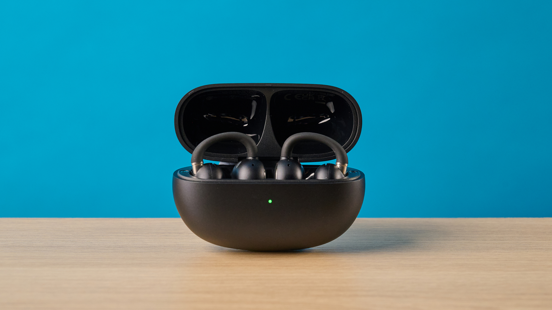 EarFun Clip 2 in black on table photographed in front of a blue background