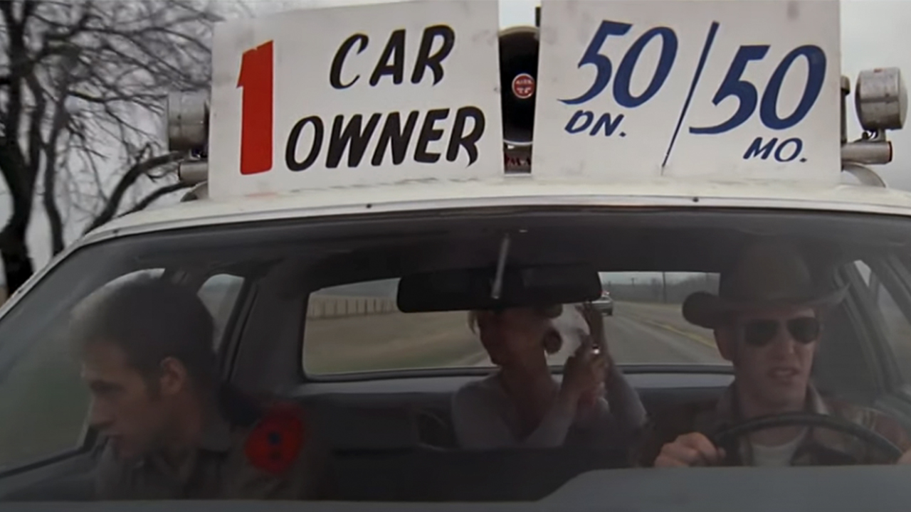 Three people in a car with signs on top in The Sugarland Express
