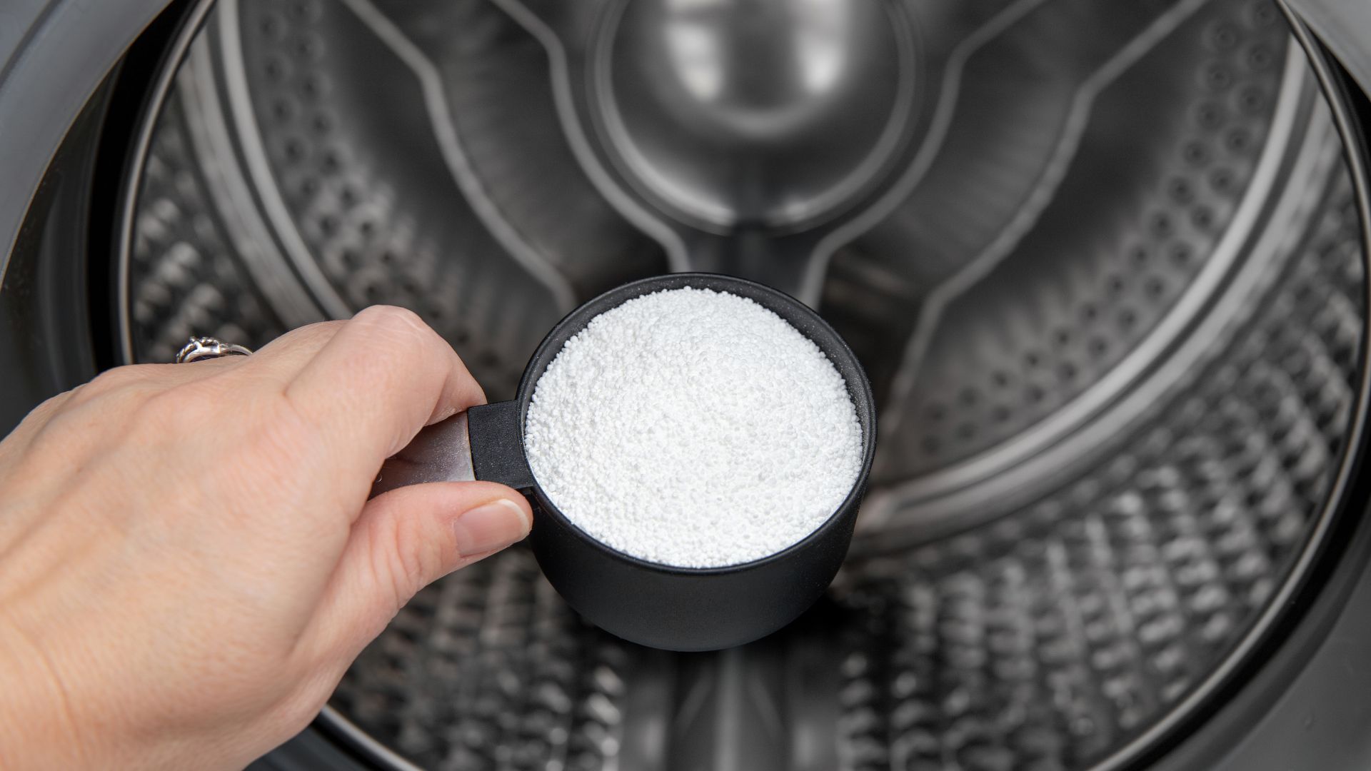picture of person putting citric acid inside washing machine drum
