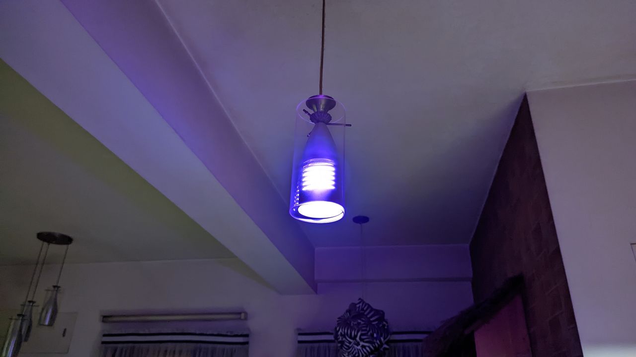 SwitchBot smart color light bulb installed in a light fixture hanging from a wall