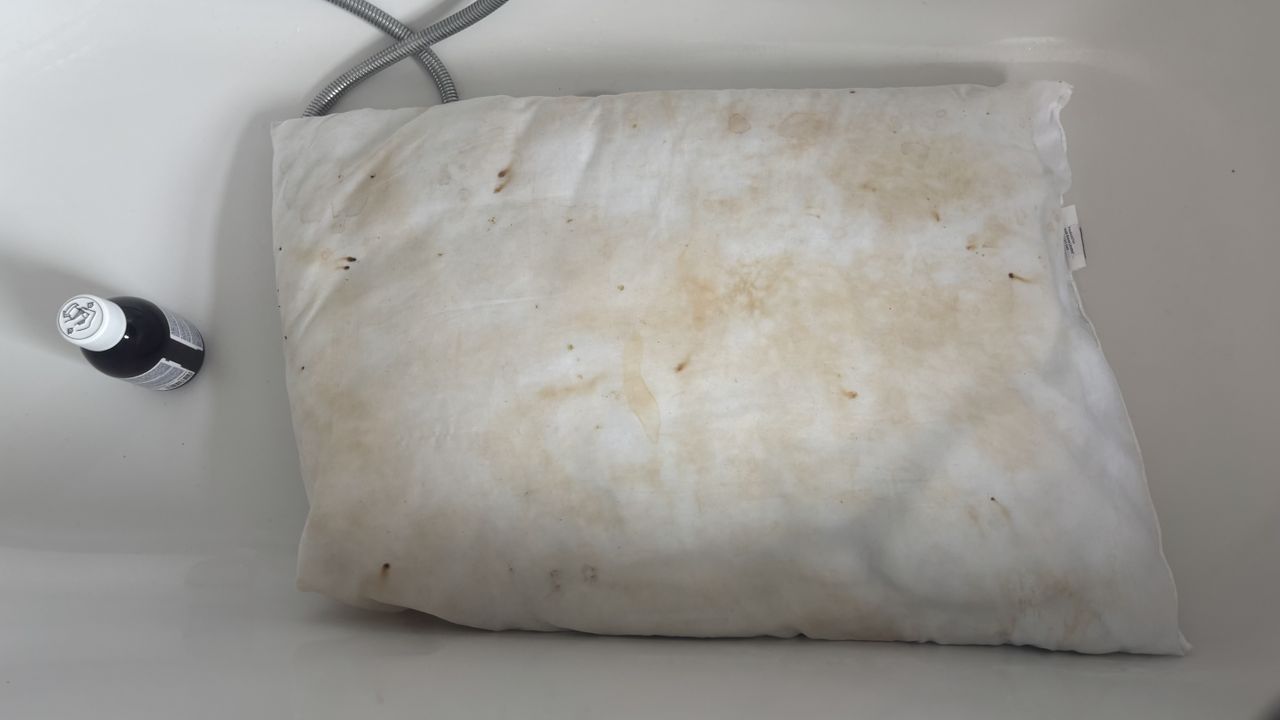 A stained pillow in an empty bathtub.