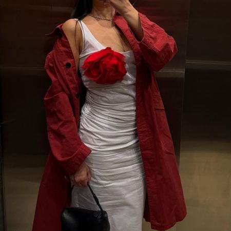@themillennialdecorator wearing a red trench coat and white dress with a flower brooch.