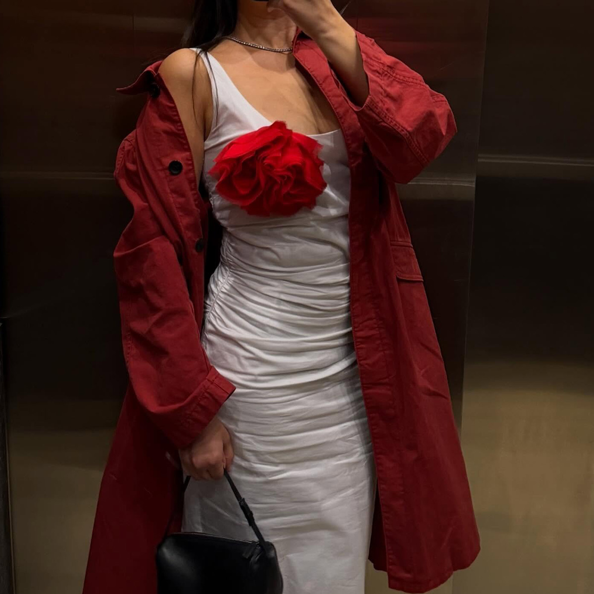 @themillennialdecorator wearing a red trench coat and white dress with a flower brooch.
