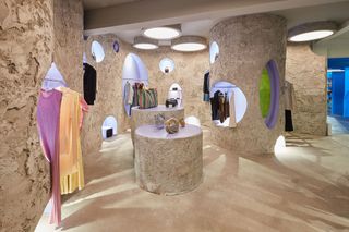 A Space Age-meets-brutalism-inspired concept store features geometric shapes and exposed rocks surfaces along with luxurious clothing.