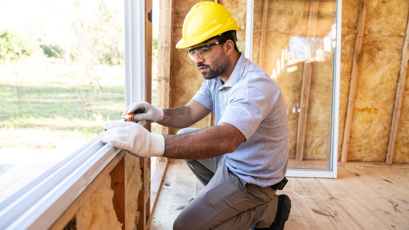 construction worker installing window frame onto insulated walls