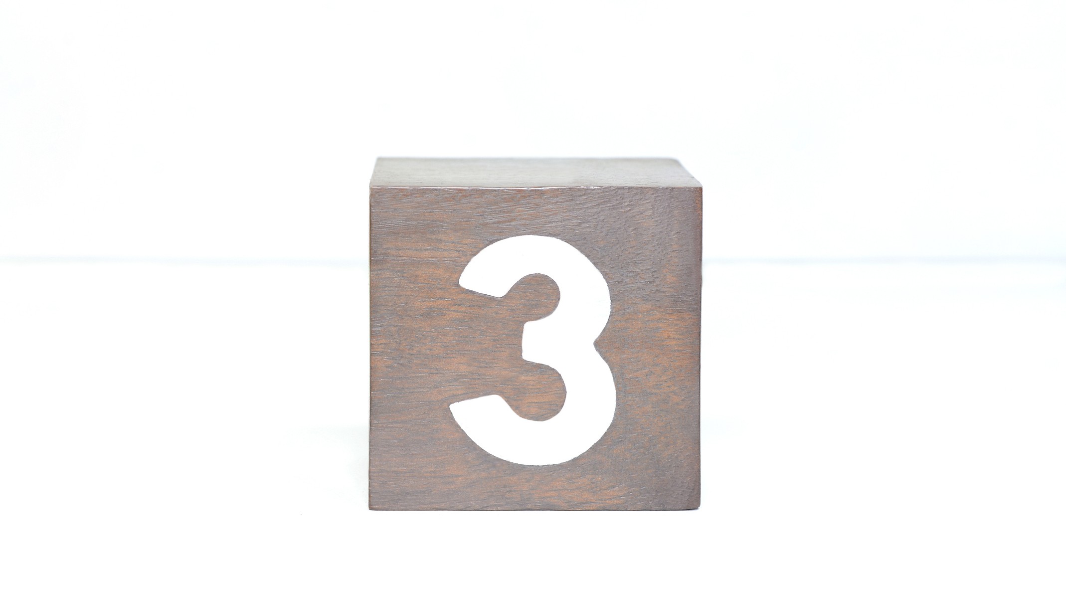 A simple wooden block with the number 3 on it.