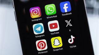 An iPhone with mobile icon apps Facebook, Instagram, WhatsApp, Telegram, TikTok, Snapchat, YouTube, Twitter X, Pinterest