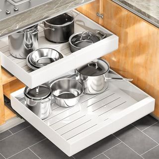 White plastic shelf pull outs in a wooden cabinet with metal pans on them 