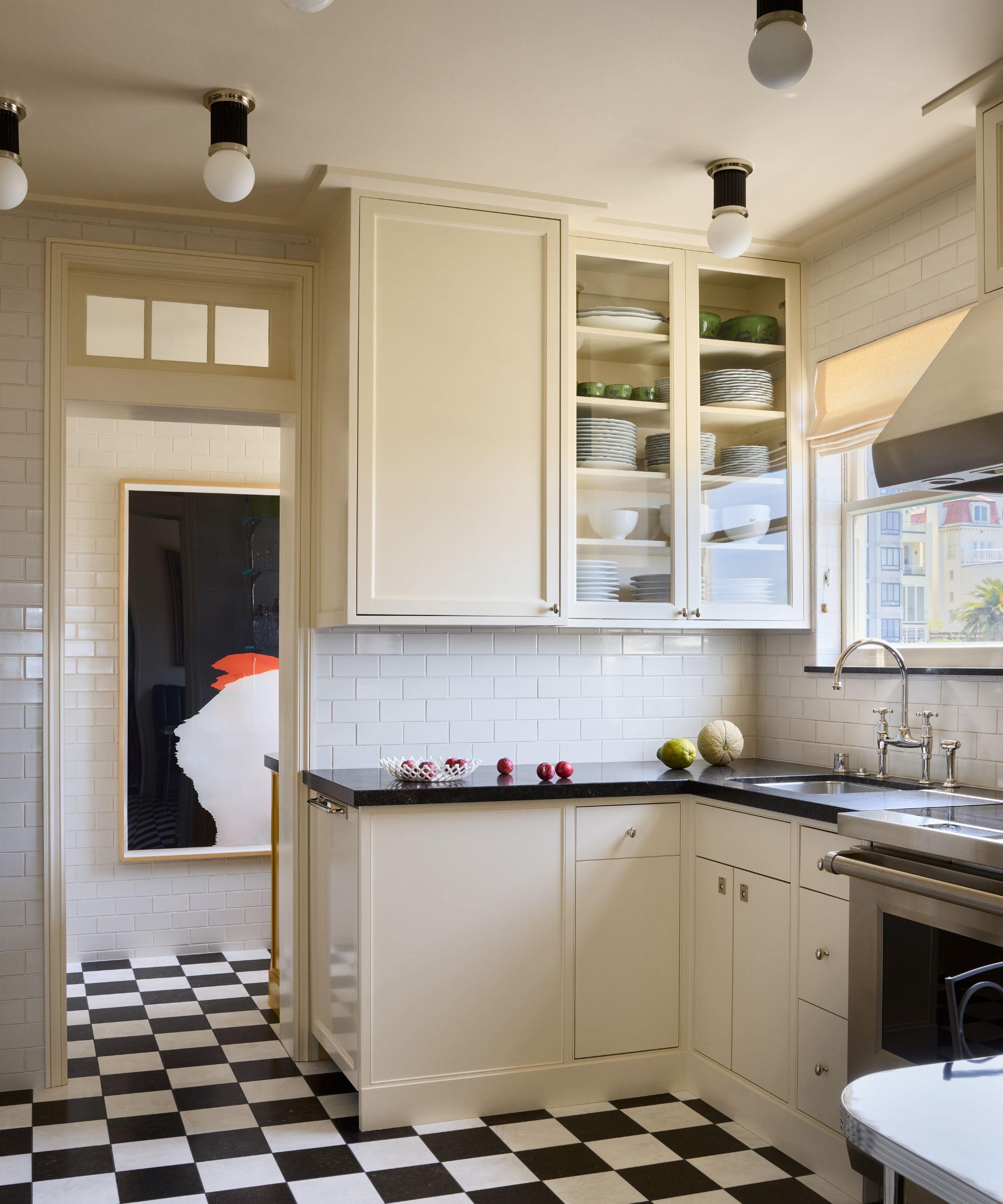 a soft off white kitchen with flat cabinetry, a glass front corner cabinet and black and white checkerboard floor tiles