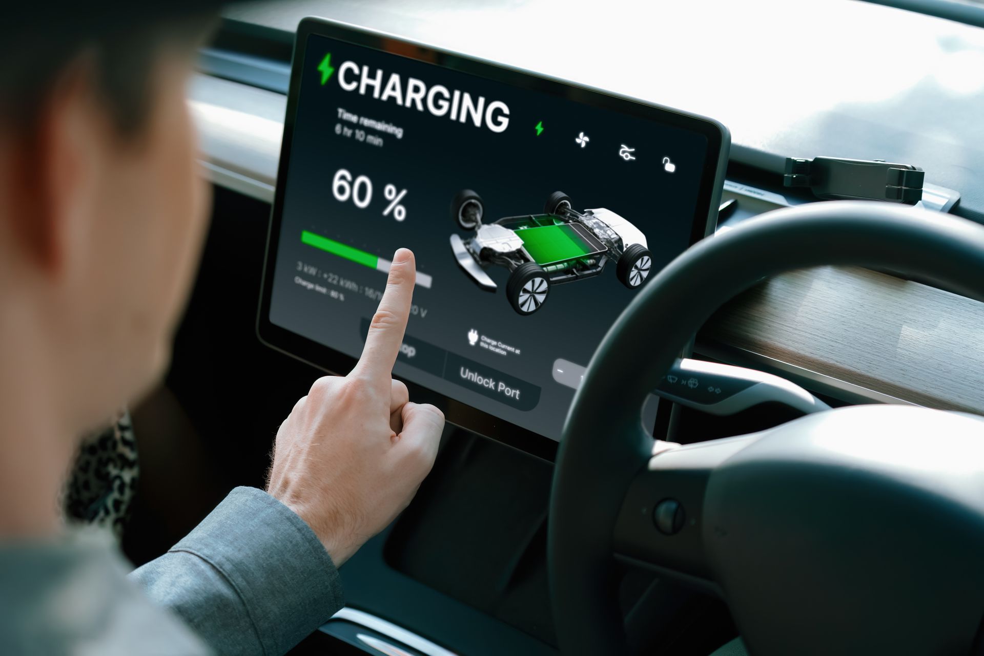 Electric car driver checks battery charging status, range and charging limit on app screen in the car.