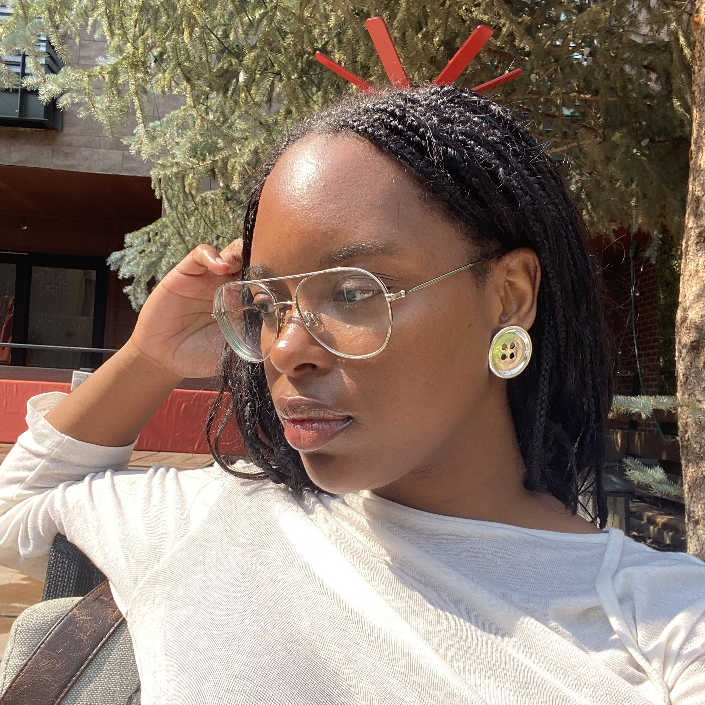 A woman wearing silver button earrings and a white longsleeve top