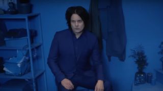 Jack White dressed in blue sitting in a blue room looking pensive.