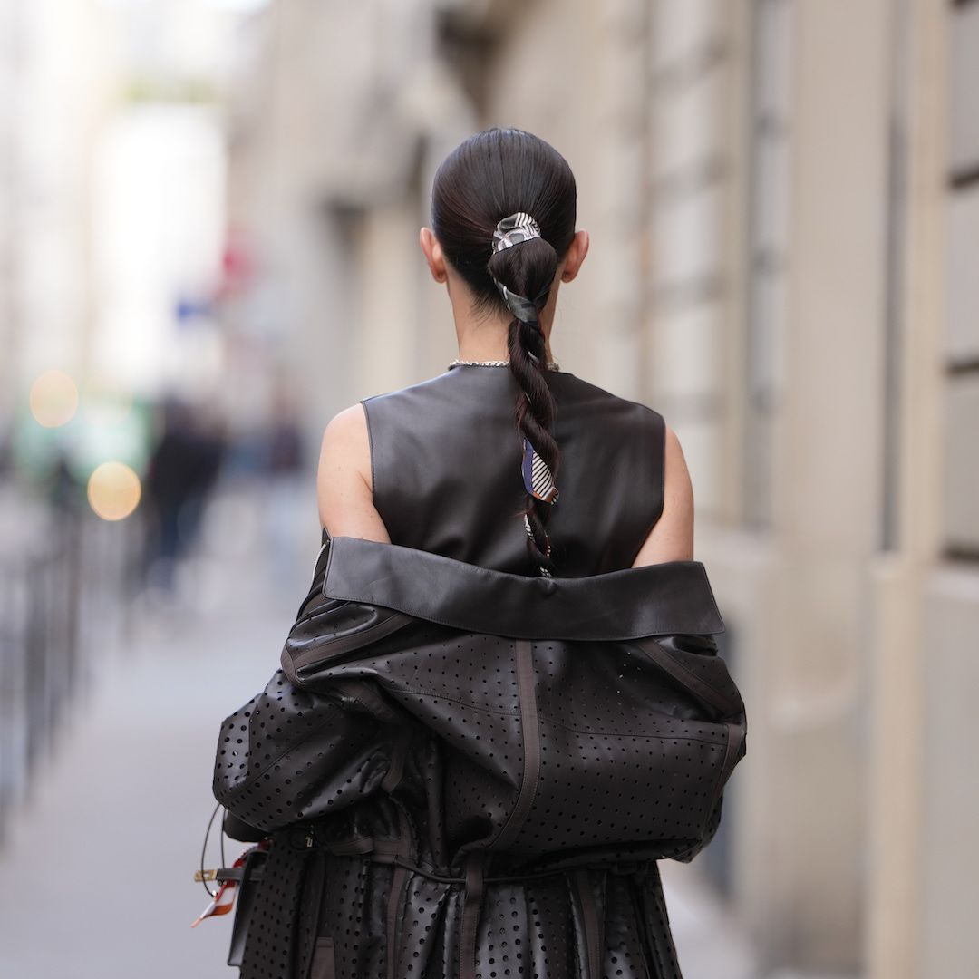 best hair ties damage-free Woman wears sleek dark brown hair pulled into a long braided ponytail with a centre part and a patterned silk scarf woven through the braid