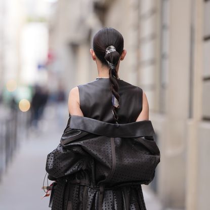 best hair ties damage-free Woman wears sleek dark brown hair pulled into a long braided ponytail with a centre part and a patterned silk scarf woven through the braid