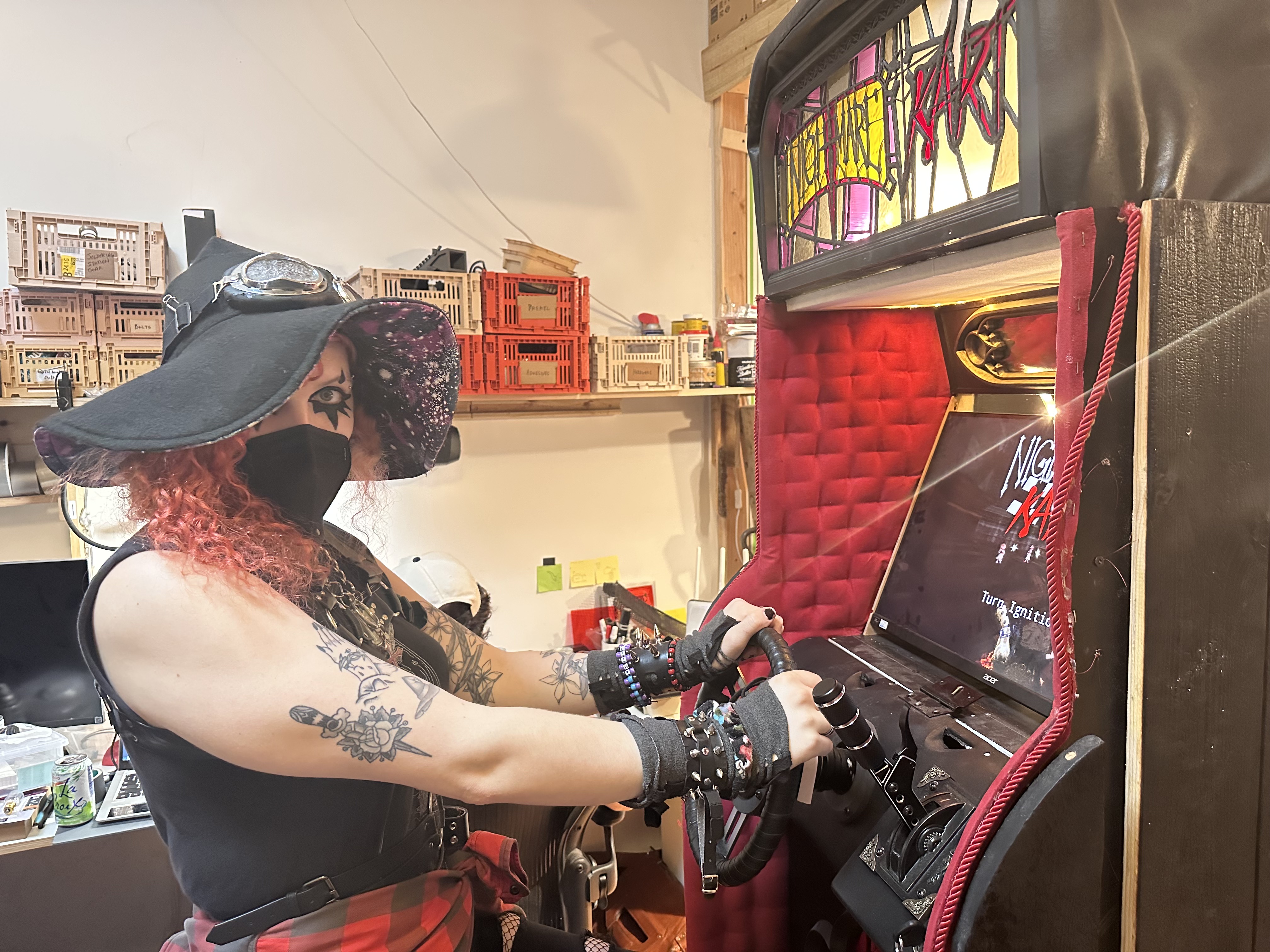Lilith Walther sits in front of the Nightmare Kart arcade cabinet at the Arcade Commons workshop