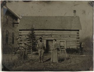 Archive black and white image of man and woman outside cabin