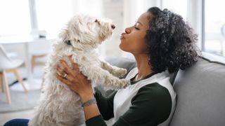 Woman giving her dog a kiss on the couch