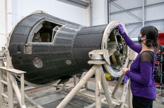 A National Air and Space Museum conservator works around the recovery compartment of Freedom 7, Alan Shepard's Mercury capsule, in the Mary Baker Engen Restoration Hangar at the Steven F. Udvar-Hazy Center in Chantilly, Virginia.