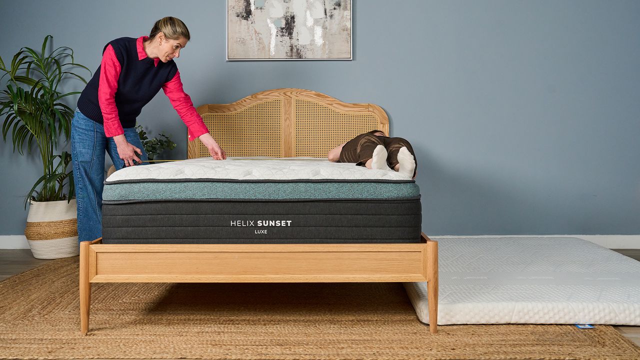 A tester rests right on the edge of the Sunset Luxr Mattress. A thin mattress is positioned on the floor next to the bed, to cushion her if she should fall off the bed.