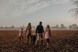family walking hand in hand across field