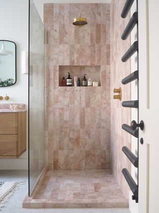 a pink marble tile shower with a tiled lip