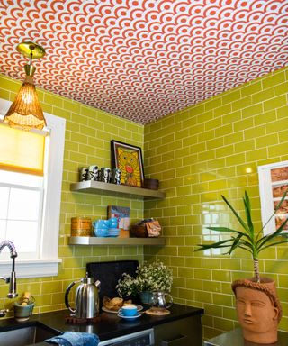 Maximalist kitchen with bold wallpaper on ceiling and green contrast wall tiles