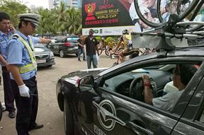 Local police show Drapac Professional Cycling team-manager Agostino Giramondo where to go in the tour parking lot in Haikou.