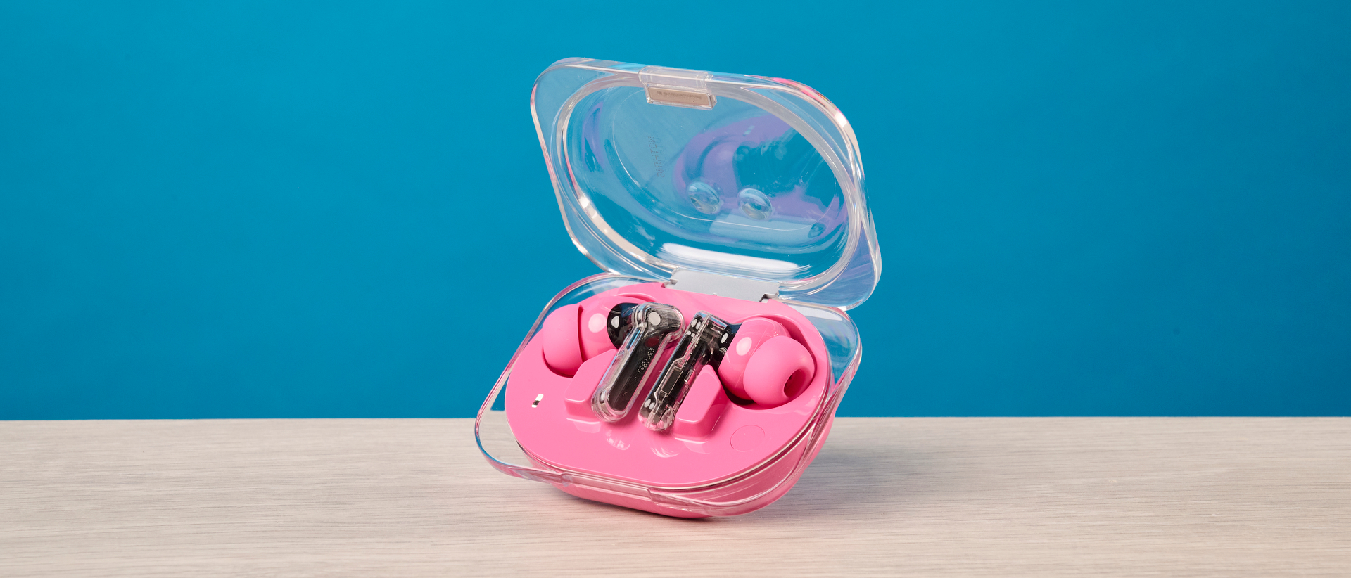 The Nothing Earbuds (3a) in pink, on a wooden surface
